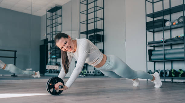 istock Focused woman using an ab roller for core workout in a gym 2010726546