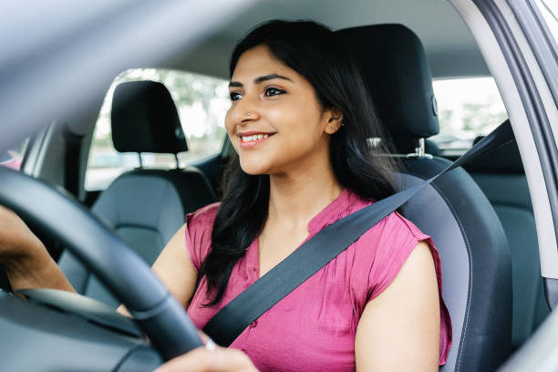 Happy indian woman driving a car in the city Happy indian woman driving a car in the city. Portrait of smiling female with safety belt traveling in her auto. happy car asian stock pictures, royalty-free photos & images
