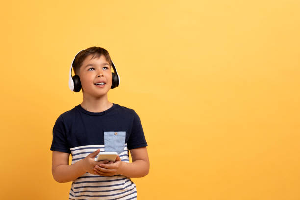 istock Happy kid shool aged boy using wireless headphones and smartphone 2010738278