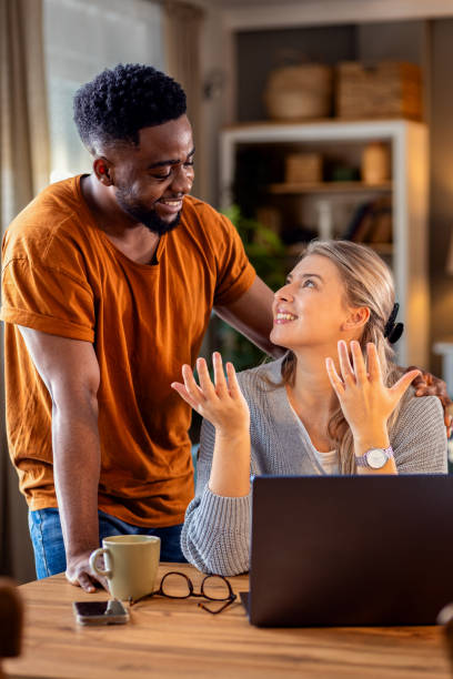 istock Smiling young mixed couple using a laptop while working on their home finances. 2010760663