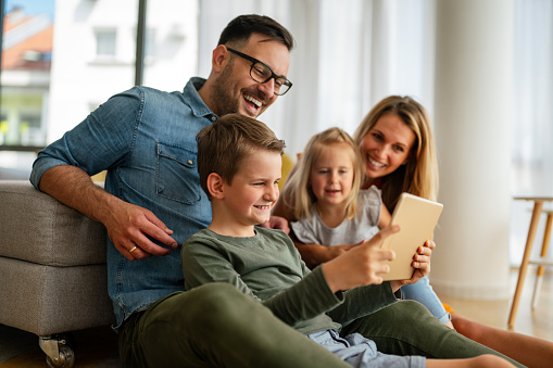 Happy young family having fun time at home. Parents with children using tablet. People love happiness concept.