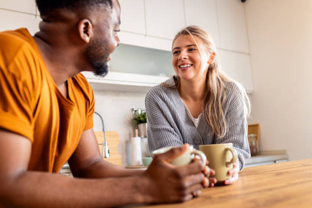 istock Smiling young mixed couple standing in kitchen drinking coffee at home. 2010762291
