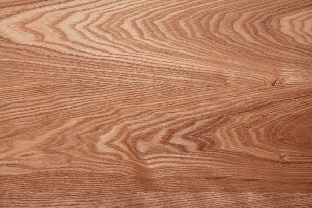 Weathered and scratched rustic wooden board.High angle view of a flat textured wooden board backgrounds. It has a beautiful nature and abstractive pattern. A close-up studio shooting shows details and lots of wood grain on the wood table. The piece of wood at the surface of the table also appears rich wooden material on it. The wood is dark brown color with darker brown lines and pattern on the bottom. Flat lay style. Its high-resolution textured quality.The close-up gives a direct view on the table, showing cracks and knotholes in the wood.
