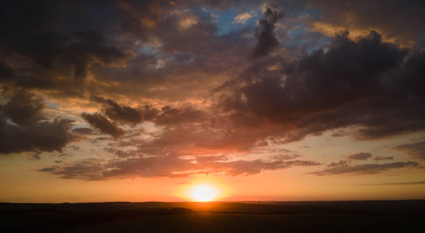 istock Bright colorful sunset sky with setting sun and vibrant clouds over dark landscape 2010766102