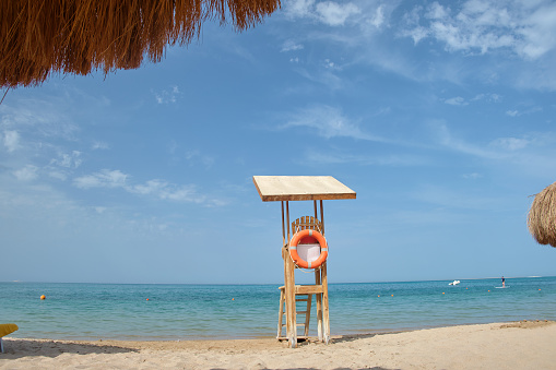 Emplty wooden lifeguard station on sandy beach on ocean shore in summer.