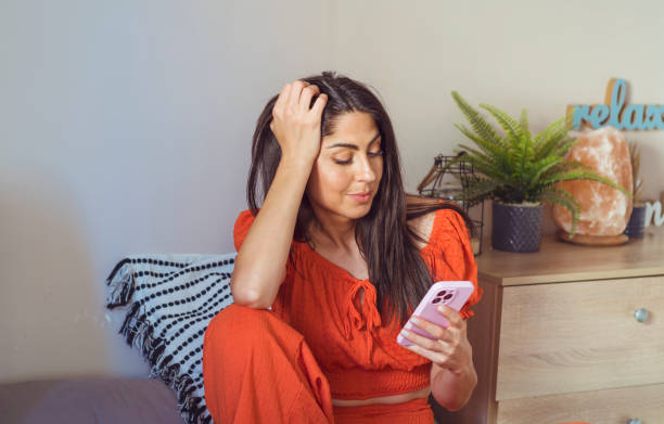 smiling woman using her phone at home - young women sitting simple living eastern europe fotografías e imágenes de stock