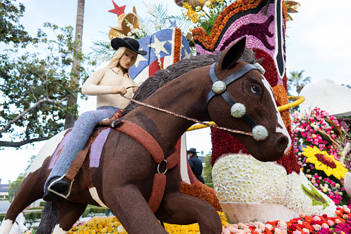 Pasadena Rose Parade float with a cowgirl riding a horse made of flowers.