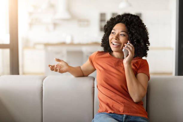 istock Beautiful Black Woman Making Phone Call While Relaxing On Couch At Home 2010782178