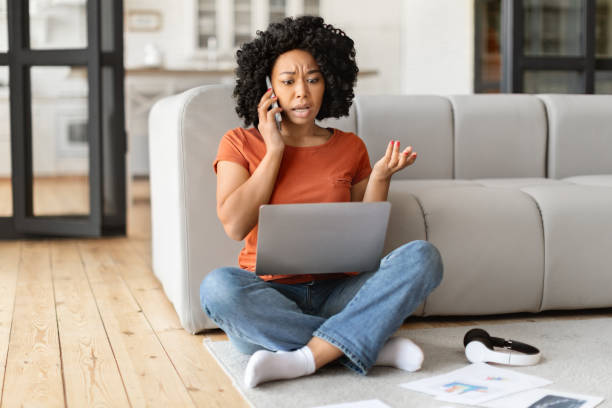 istock Black woman suffering problems with laptop at home, calling to customer support 2010782217