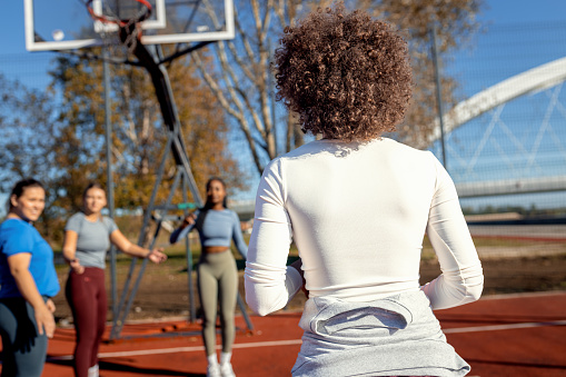 Diverse group of young woman having fun playing recreational basketball outdoors.