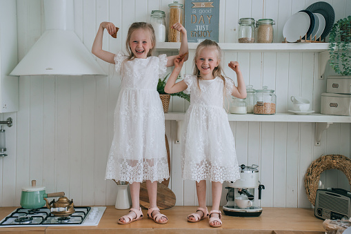 Twin girls laughing in a rustic kitchen setting