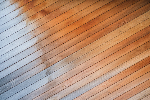 A fading, water-stained, brown wood paneled floor with diagonal slats.