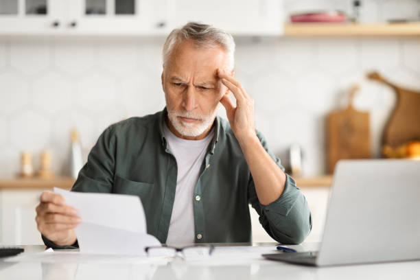 istock Distressed elderly man touching head, feeling overwhelmed when doing paperwork at home 2010826460