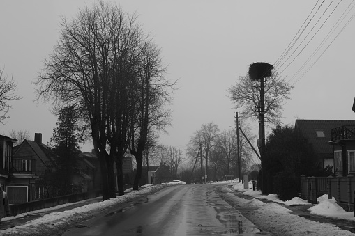 Zarasai, Lithuania - 02 08 2024:  Black and white photography. City street with lots of melting snow and water.