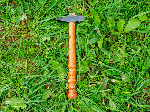 Close-up of an old hammer lying on the green grass. Top view, flat lay