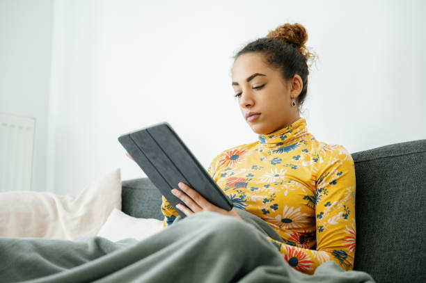 istock Woman reading using digital tablet wrapped in blanket at home 2010849853
