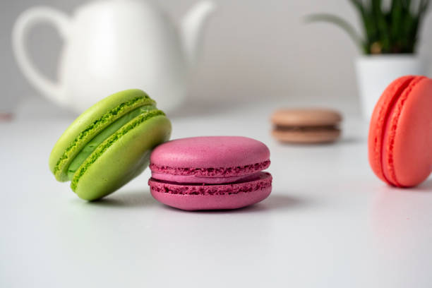 istock Colorful delicious macaroons lie on a white table. In the background is a white teapot and a flower 2010850916