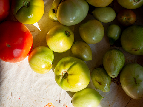 unripe green tomatoes spread out on the table. Top view, flat lay