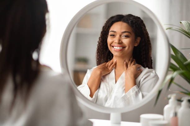 istock Attractive Black Woman Touching Soft Skin On Neck While Looking In Mirror 2010866493