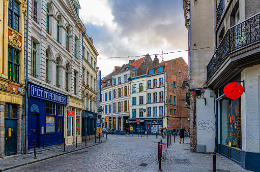 Lille, France, July 3, 2023: Empty narrow cobblestone street with stores, paving stone road, old colorful buildings shops with signboard in historical city centre, French Flanders, Nord department