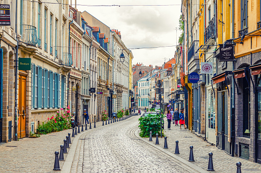 Lille, France, July 4, 2023: cobblestone street with stores, paving stone road, old colorful buildings shops with signboard in historical city centre, Nord department, Hauts-de-France Region