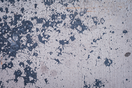 Splatters of black paint on light gray cement,