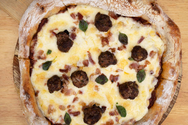 Top view of a delicious pizza with mozzarella cheese, crispy bacon, tomato sauce and meatballs.