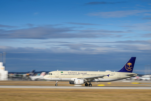 Munich, Germany - February 14. 2024 : Saudi Arabian Airlines Airbus A320-214 with the aircraft registration HZ-ASC is starting on the southern runway 26L of the Munich airport MUC EDDM