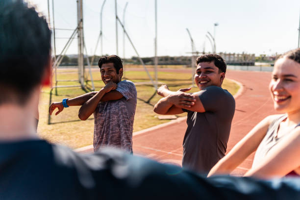 Athletes talking and stretching on track and field stadium
