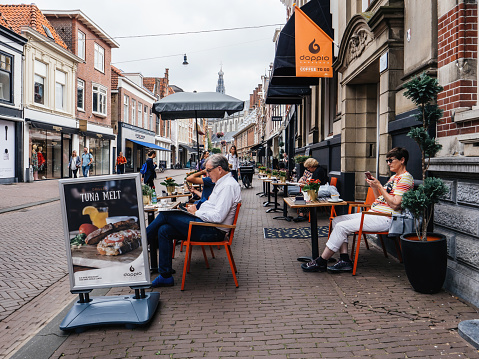 Haarlem, The Netherlands - Jul 21, 2018: Dutch street scene with large open terrace people eating, drinking tea and coffee at the Doppio coffee to go bar terrace with fresh grilled tuna meat advertising