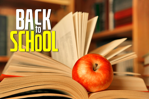 Close-up of a red apple on an open book with BACK TO SCHOOL lettering.
