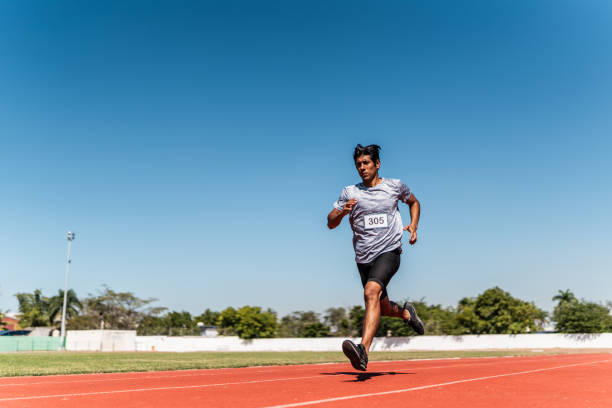 mid adult athlete man running on track and field stadium - track and field 30s adult athlete photos et images de collection