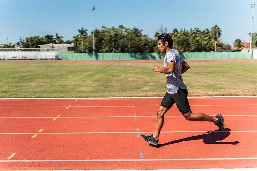 Mid adult athlete man running on track and field stadium