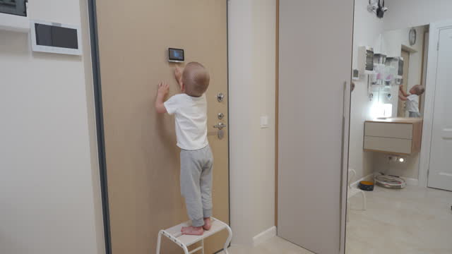little boy looking through intercom screen of door peephole surveillance camera