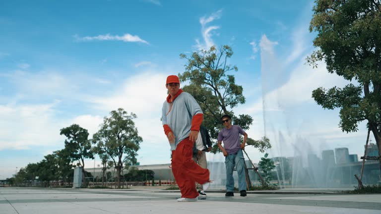 Asian skilled hipster doing freeze pose at camera near fountain. Sprightly.