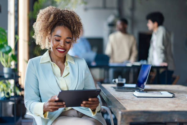 istock Smiling Businesswoman Using Tablet in Modern Office Space 2011075807