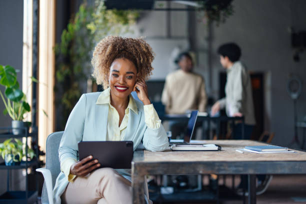 istock Smiling Businesswoman Using Tablet in Modern Office Space 2011075815