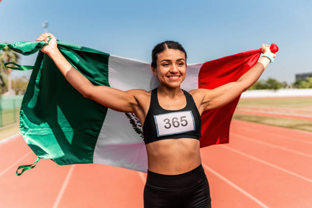 femme athlète adulte tenant un drapeau mexicain et célébrant sur une piste de sport - track and field 30s adult athlete photos et images de collection