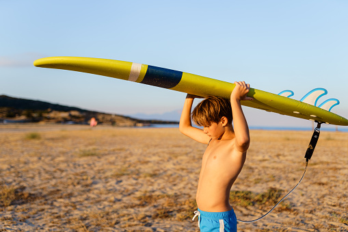 Portrait of a teenage boy holding  surfboard on the beach