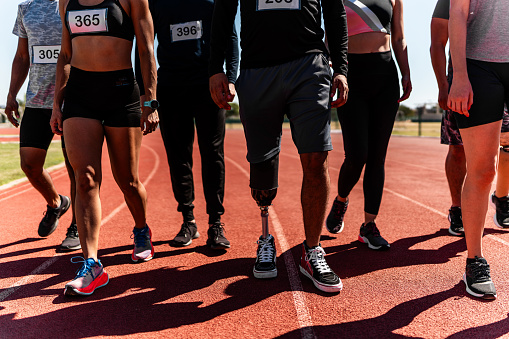 Low section of athletes walking on sports track - Including athlete with disabilities