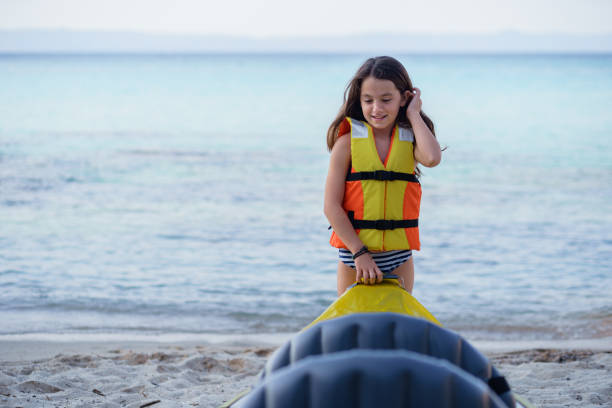 girl having fun with inflatable kayak on her summer cam vacation - summer camp child teenager kayak - fotografias e filmes do acervo