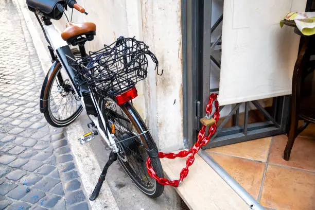 Urban security: a bicycle locked with a red chain outside a cafÃ©, highlighting theft prevention measures
