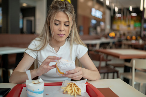 Gourmand Girl Eating Tasty Hamburger at Fast Food Restaurant