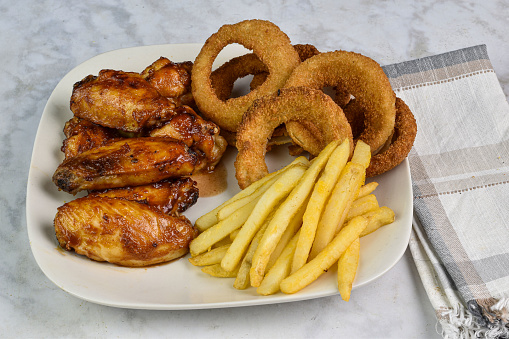 chicken wings top with barbecue sauce  served with onion rings and fries