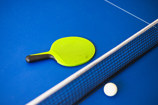 Blue ping pong table. Ping pong racket and ball. The concept of sport and healthy lifestyle.