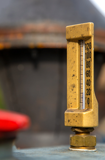 Old brass thermometer on the engine cooler of a  vintage tractor