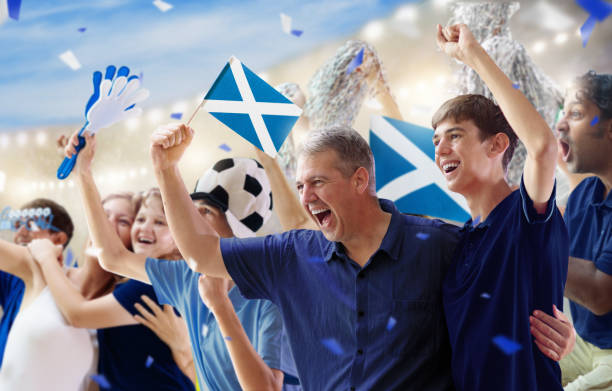 Scotland football team supporter on stadium. Scotland football supporter on stadium. Scottish fans on soccer pitch watching team play. Group of British supporters with flag and national jersey cheering for UK. Championship game. Go Scotland! scotland football team stock pictures, royalty-free photos & images