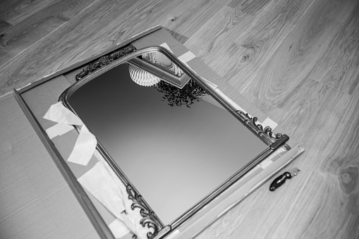 black and white Unboxing inspecting new vintage wooden luxury framed mirror delivered without any flaws in the cardboard package - security safety during transportation