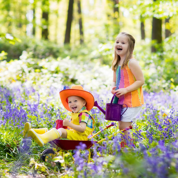 One year old little girl sat on a log in a Bluebell wood called Pamphill in Dorset.