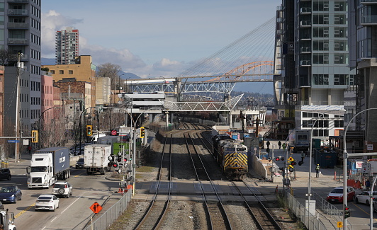 New Westminster, Canada - February 9, 2024: View from River Market walkway above the train tracks between Front Street and Quayside Drive. A level crossing extends along Begbie Street. Canadian National CN3967 is heading northwest from downtown. Winter morning in Metro Vancouver.